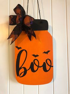 a wooden sign that says booo hanging from a wall with a bow on it