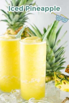 two glasses filled with pineapple juice on top of ice next to sliced pineapples