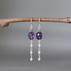 "Faceted Purple Amethyst oval stones are wire wrapped with silver wire and topped with detailed Bali Silver caps. Cascading from these are petite faceted Clear Cubic Zirconia buttons. These dangle from balled silver earwires. Wonderful delicate long earrings to wear everyday! Purple Amethyst stones: 7x10mm Cubic Zirconia buttons: 3x2mm Total length of earrings: 2\" All silver is sterling. As the owner, maker, designer, and curator of this shop, I take great pride in providing you with jewelry th Purple Oval Earrings With Gemstone Accents, Gemstone Accented Dangle Earrings, Oval Amethyst Earrings With Gemstone Accents, Purple Gemstone Accented Drop Earrings, Purple Drop Earrings With Gemstone Accents, Adjustable Oval Sterling Silver Earrings, Purple Oval Earrings For Weddings, Elegant Amethyst Chandelier Earrings For Gift, Sterling Silver Drop Earrings With Gemstone Accents