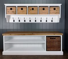 a white bench with baskets on it next to a wall mounted coat rack and storage bins