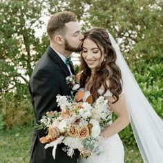 a bride and groom kissing in front of trees