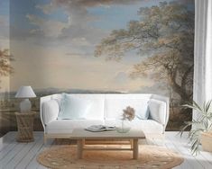 a living room with a white couch and large painting on the wall above it's windows