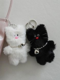 two small stuffed animals sitting next to each other on a pink purse strap with a keychain