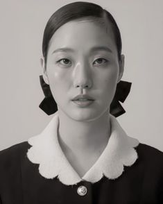 a black and white photo of a woman with large earrings on her head, looking at the camera