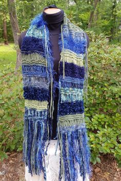 Hand knit crazy scarf made with multiple yarn textures and embellished with long fringe Size: Scarf body is 55 inches long with 12 inches of fringe at each end for a 79 inches total length x 8 inches wide Colors: hues of blue and green Acrylic, nylon,mohair, cotton, polyester, polyamide Hand wash, cool, no bleach; lay flat to dry away from direct sun CSFr1 Blue Knitted Yarn Scarf, Blue Handmade Bohemian Scarves, Blue Bohemian Scarf With Natural Dye, Funky Scarves, Handmade Blue Yarn Scarf, Yarn Projects Crochet, Bohemian Scarves With Fringe, One Size, Boho Jeans, Chic Scarves