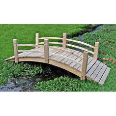 a wooden bridge over a small stream in the grass