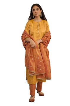 Warm yellow plain kurta. Paired with a pant. Comes along with a rust dupatta with hand embroidery and kiran lace border. - Aza Fashions Festival Tussar Silk Palazzo Set With Straight Kurta, Diwali Tussar Silk Palazzo Set With Straight Kurta, Raw Silk Set With Dupatta For Puja, Tussar Silk Straight Kurta Sets For Festivals, Festival Tussar Silk Straight Kurta Sets, Transitional Chanderi Churidar, Raw Silk Churidar With Dupatta, Fitted Tussar Silk Sets For Puja, Diwali Tissue Silk Churidar With Straight Kurta