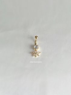 a gold charm with a flower on the bottom and a small diamond in the middle