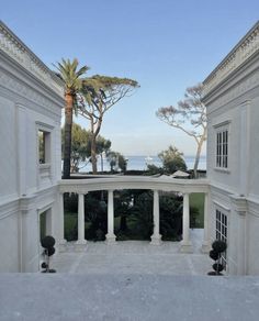 an outdoor area with columns and palm trees in the foreground, looking out onto the ocean