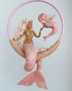 an ornament made to look like a mermaid sitting on the moon with pink hair