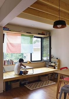 a person sitting at a desk in front of a window with bookshelves on it