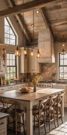 a large kitchen with an island in the middle of it and lots of lights hanging from the ceiling