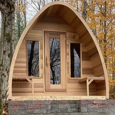 a large wooden sauna in the middle of a forest with trees and leaves around it