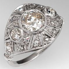 an antique style diamond ring with filigrees on the sides and round diamonds in the center