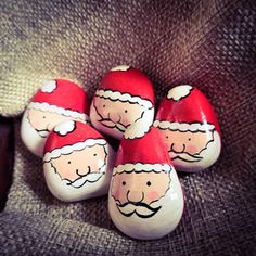 five santa clause painted rocks sitting on top of a gray cloth covered chair with the seat up