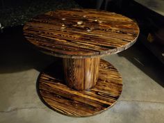 a round wooden table sitting on top of a cement floor