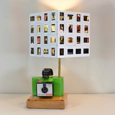 a green camera sitting on top of a wooden table next to a lamp with pictures on it