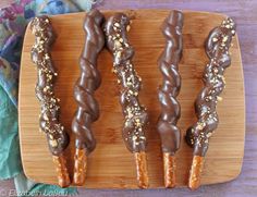 four chocolate covered donuts on a wooden platter