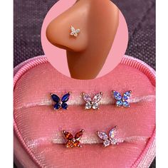 three pairs of butterfly shaped studs in a pink heart - shaped case with an image of a woman's breast