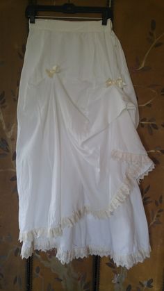 "80's hand made one of a kind white cotton ruched / ruffled bo peep style maxi skirt. High waits with metal popper buttons at sides. Skirt has 2 cream ribbon bows on one side with ruched up fabric and one on the other side. There are two layers of fabric with a cream lace hem which goes up to the ribbon on one side. Really lovely one of a kind. The inside fabric next to popper buttons is abit frayed but can't be seen when done up! :) waist 26\", hips 36 / 38, skirt length 38\"" Spring Wedding Maxi Skirt With Ruffles, Summer Wedding Ruffled Maxi Skirt, Vintage White Skirt With Attached Cancan, Summer Cotton Skirt With Attached Cancan, White Cotton Maxi Skirt With Ruffles, Summer Wedding Maxi Skirt With Gathered Details, White Ruffled Maxi Skirt For Daywear, White Fitted Lace Maxi Skirt, Fitted White Lace Maxi Skirt