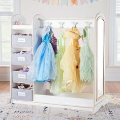 three baby dresses hanging on a rack in a room