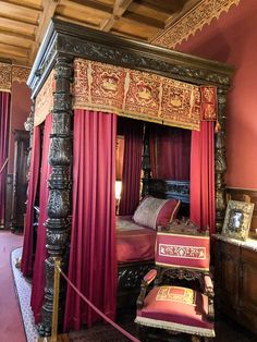 a canopy bed with red drapes and pillows