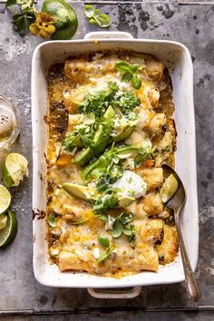 a casserole dish with vegetables and cheese on top, next to sliced limes