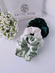 two scrunffle hair ties sitting on top of a white table next to a bouquet of flowers