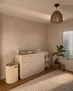 a baby crib next to a window in a room with a rug and potted plant