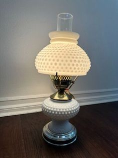 a lamp that is on top of a wooden table next to a wall and floor