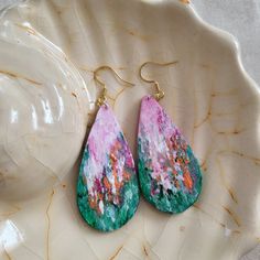 a pair of pink and green earrings sitting on top of a white plate