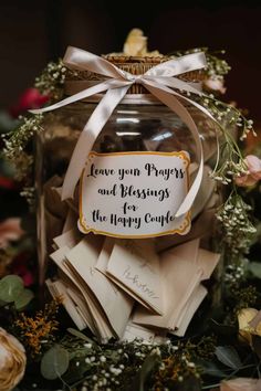 a jar filled with lots of cards and paper on top of a pile of flowers