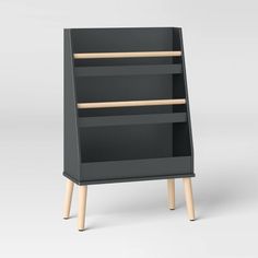 a black bookcase with two wooden legs and an open shelf on one side, in front of a white background