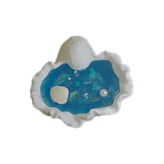 a blue and white shell shaped dish with shells on it's rim, in the shape of a seashell