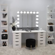 a white vanity with lights on it and a stool