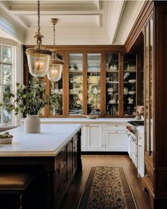 a large kitchen with lots of windows and white counter tops, along with an area rug on the floor