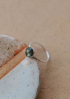 Our Dori ring is made with a gorgeous Labradorite stone. This mystical gemstone is believed to enhance mental clarity and bring about transformation. It's a crystal connected to the third eye chakra which is our gateway to inner wisdom and deeper intuition. 8mm round or 6x8mm oval labradorite stone. Ring band measures 1mm wide. Available in 14kt Gold Fill + Sterling Silver. KJ pairs it with our Sonder Ring, Raye Ring, and Confetti Ring. Handmade in Eau Claire, WI. Our jewelry is handmade so each piece will be unique and may vary slightly from what is pictured. Confetti Ring, Copper Uses, Everyday Wear Jewelry, Backdrops Necklace, Zodiac Rings, The Third Eye, Hoop Charms, Inner Wisdom, Third Eye Chakra