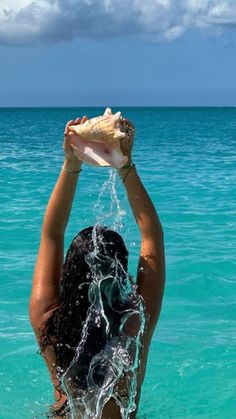 a woman in the ocean holding up a shell