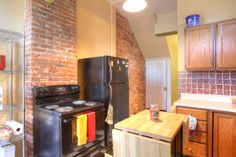 a kitchen with an oven, refrigerator and microwave next to a brick wall in the background