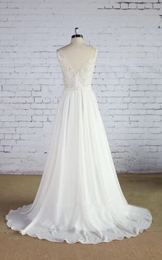 a white wedding dress on a mannequin in front of a brick wall and floor