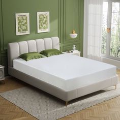 a white bed sitting in a bedroom on top of a hard wood floor next to a green wall