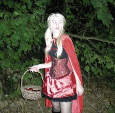 a woman dressed as a red riding hood and holding a wicker basket in her hand