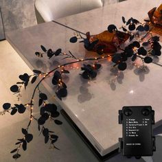 the table is decorated with black flowers and lights, along with a phone charger