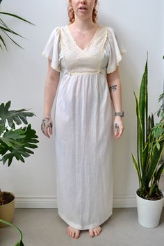 Vintage Cream Gauzy Maxi Dress. Wrapped Lace Bib. Flutter Sleeves With Lace Trim. Tie Back Waist. Zipper Closure in Back. Unlined.  No Content Label  No Size Tag  Excellent Vintage Condition - Faint Marks All Measurements Taken Flat Chest-17"  Waist-15.5"  Hips-20" approx  Shoulder to Hem-56" All Sales Are Final. We have taken the time to note all size measurements and the condition of each piece so please look over all the information of the garment you are considering purchasing. Please note t Short Sleeve Maxi Dress With Lace Trim For Daywear, Short Sleeve Lace Trim Maxi Dress For Day, Short Sleeve Maxi Dress With Lace Trim, Fitted Beach Dress With Butterfly Sleeves, Daywear V-neck Lined Maxi Dress, White Flutter Sleeve Maxi Dress For Daywear, Bohemian Fitted Dress With Butterfly Sleeves, Vintage White V-neck Maxi Dress, Cream Bohemian V-neck Dress