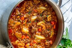 a pot filled with meat and vegetables on top of a table next to a spoon