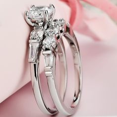 two wedding rings sitting next to each other on top of a pink flowered box