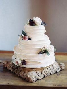 a three tiered white wedding cake with flowers on top