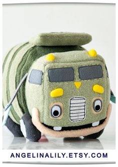 a green toy truck with yellow eyes on it's face and nose, sitting next to a white background