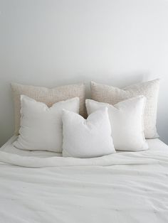 a white bed with four pillows on it