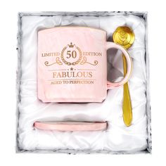 a pink and gold 50th birthday gift set in a box with a spoon, fork and mug